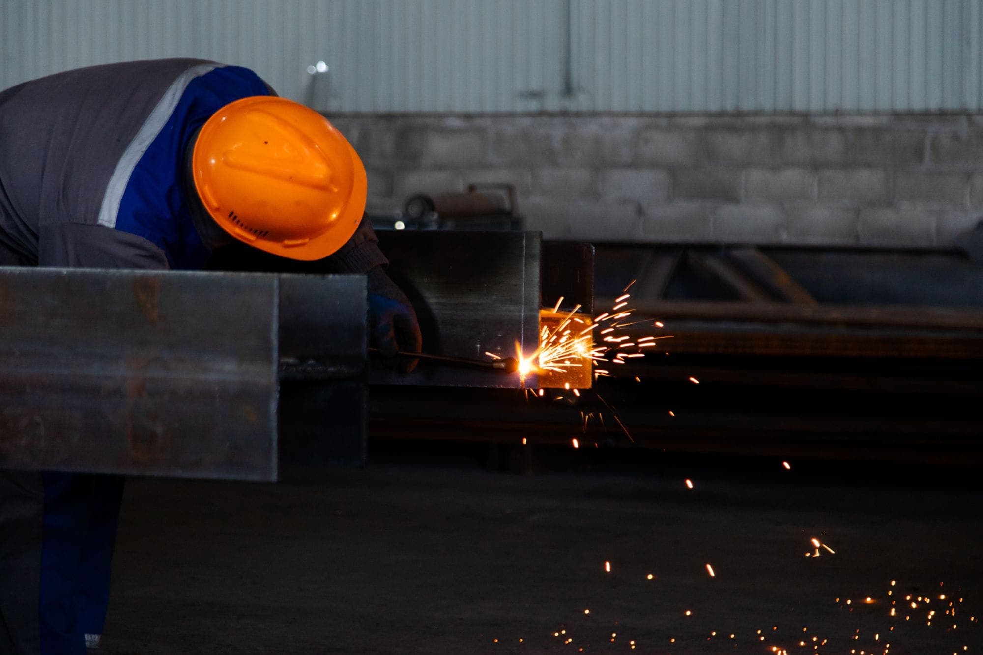 Worker welding a steel beam in a factory